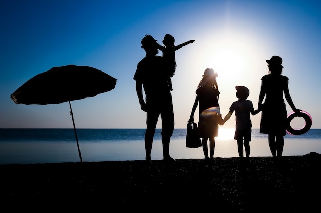 Een gelukkige familie aan zee bij zonsondergang in reissilhouet in de natuur