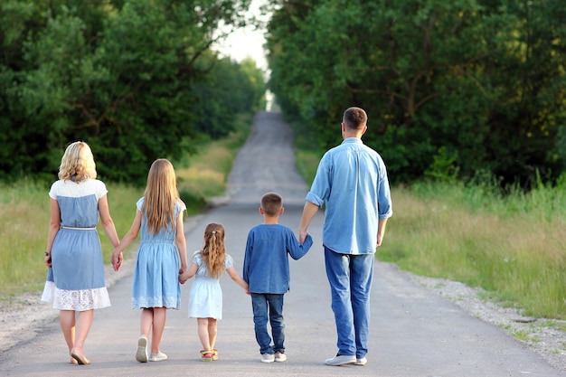 Een gelukkige familiewandeling langs de weg in het park op de natuurachtergrond