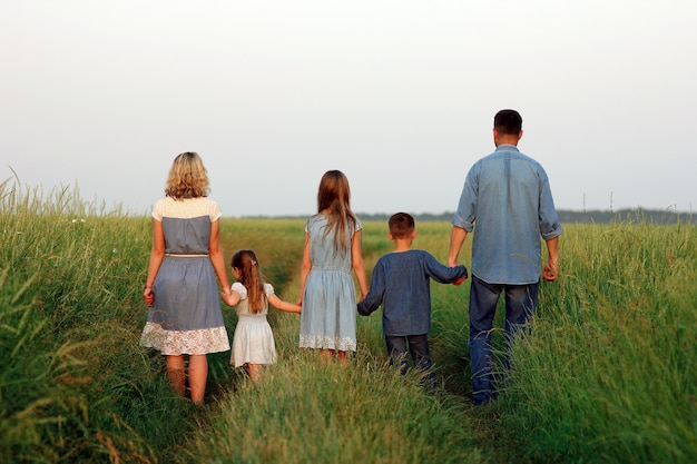 Een gelukkige familiewandeling langs de weg in het park op de natuurachtergrond