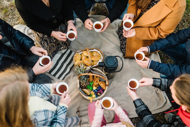 Foto een gelukkige grote familie heeft een picknick in de natuur in de herfst mama papa kinderen oma en opa drinken thee en eten croissants bovenaanzicht van een groep mensen die samen ontbijten proost