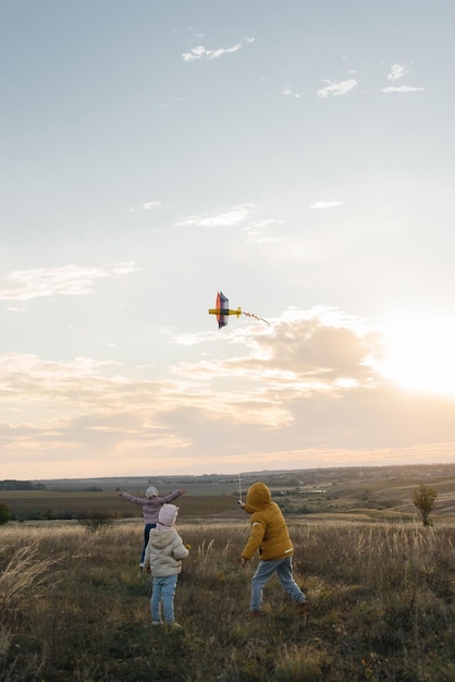 Een gelukkige jongen met zijn gezin vliegt een vlieger en brengt samen tijd door in de frisse lucht Gelukkige jeugd en openluchtrecreatie met het hele gezin