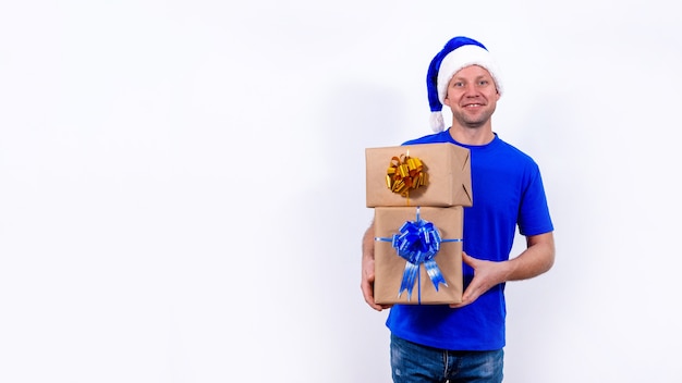 Een gelukkige koerier in een blauw uniform en kerstmuts heeft twee geschenkdozen met strikken