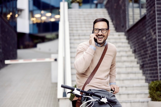 Een gelukkige man op de fiets die de telefoon op straat beantwoordt