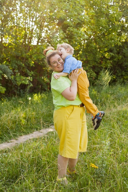 Een gelukkige moeder en een gehandicapt kind zitten op het gras in het park en knuffelen zachtjes. Zomervakantie. Onbekwaamheid.