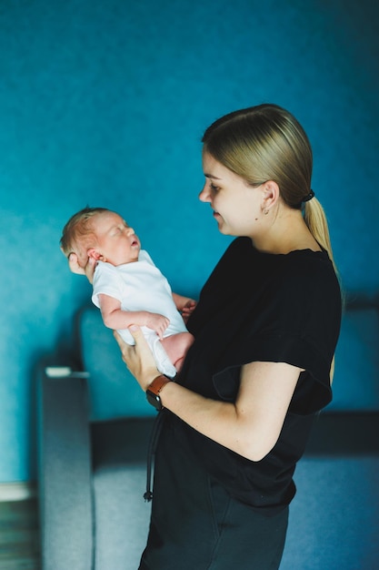 Een gelukkige moeder houdt een pasgeboren baby in haar armen Een jonge moeder knuffelt een pasgeboren baby Moeder en kind thuis