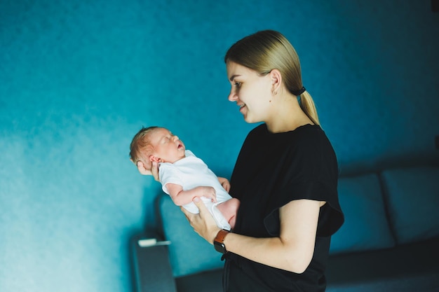 Een gelukkige moeder houdt een pasgeboren baby in haar armen Een jonge moeder knuffelt een pasgeboren baby Moeder en kind thuis