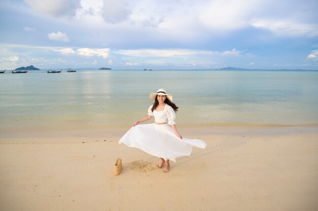 Een gelukkige mooie vrouw in witte jurk die geniet en ontspant op het strand