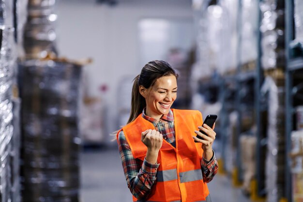 Een gelukkige opslagmedewerker viert succes en lacht aan de telefoon