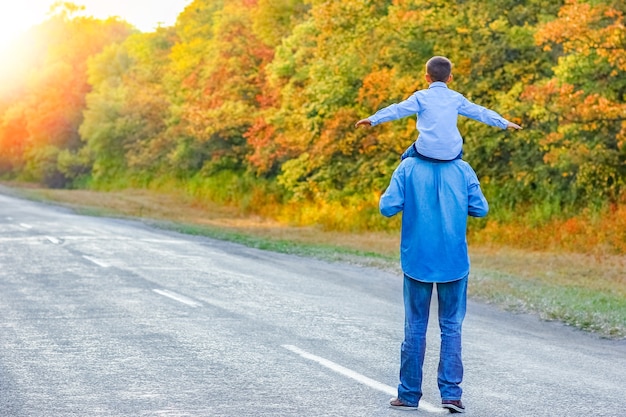 Een gelukkige ouder met een kind in het park gaat langs de weg op natuurreis