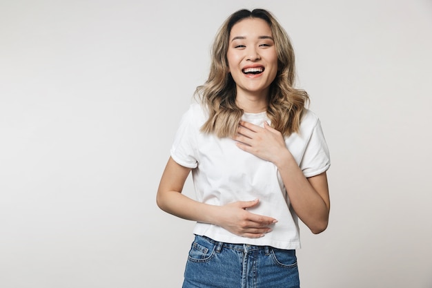 een gelukkige schattige jonge vrouw poseren geïsoleerd over een witte muur muur