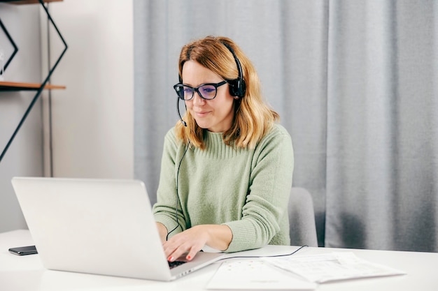 Een gelukkige telewerker van middelbare leeftijd die thuis op haar laptop werkt