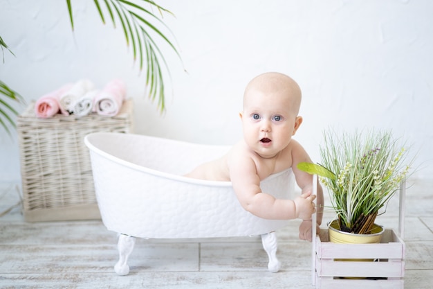 Een gelukkige, tevreden baby ligt in een bad, baadt, lacht, kijkt naar de camera