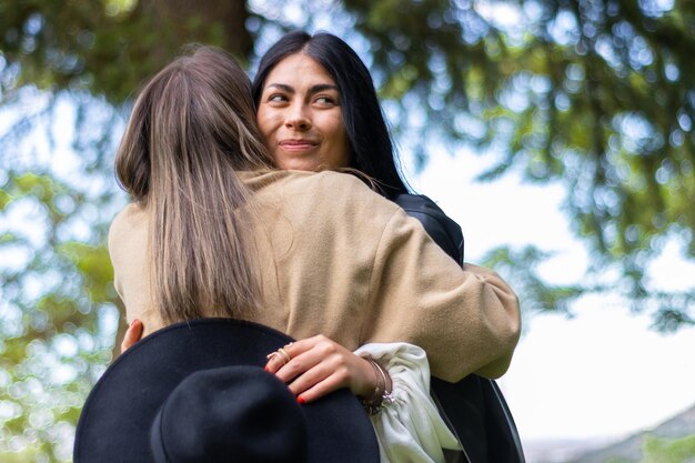 Een gelukkige vrouw die haar vriend omhelst in het park terwijl ze haar hoed vasthoudt