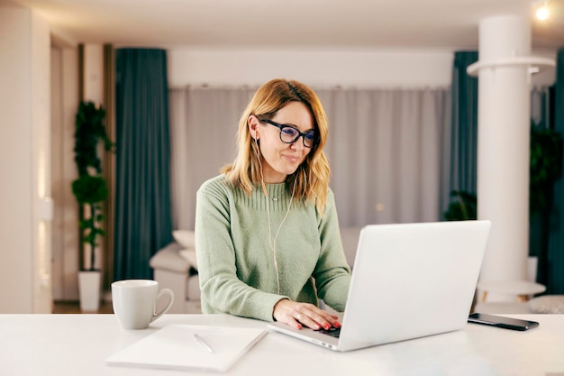 Een gelukkige vrouw die op een laptop typt en online werkt vanuit huis