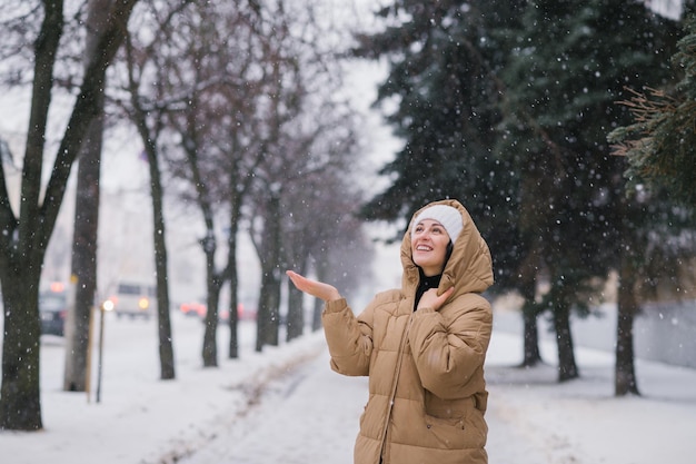 Een gelukkige vrouw in een kapmantel Het staat in de stad in de winter onder de sneeuw