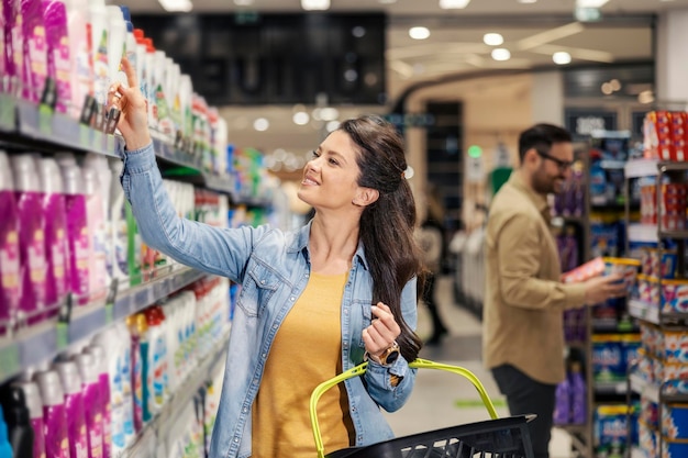 Een gelukkige vrouw koopt wasmiddel in de supermarkt