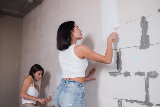 Een gelukkige vrouw maakt reparaties thuis vrienden schilderen de muren in een nieuw appartement hoogwaardige foto