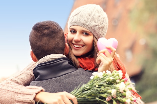 een gelukkige vrouw met een valentijnscadeau en bloemen die haar man knuffelt