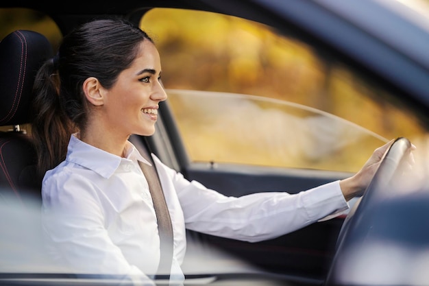 Een gelukkige vrouwelijke chauffeur rijdt een auto.