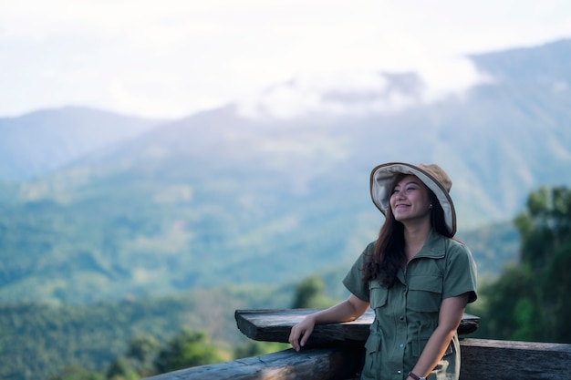 Een gelukkige vrouwelijke reiziger met een prachtig groen berglandschap op mistige dag