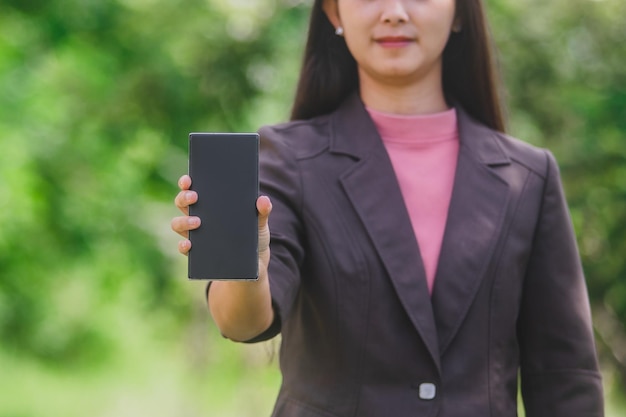 Een gelukkige zakenvrouw in een staande in een park en een telefoongesprek. Ze houdt takeaw vast