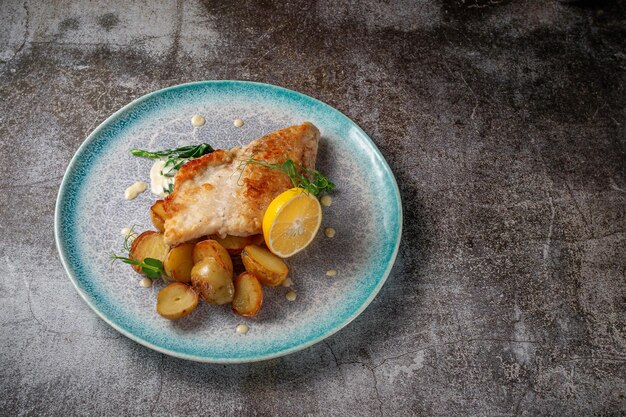 Een gerecht serveren van een restaurantmenu. Gebakken forel steak met citroen, salade en dille en peterselie greens op een bord tegen een grijze stenen tafel