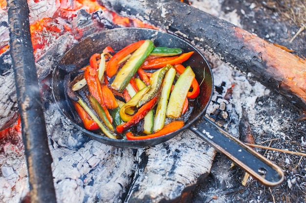 Een gerecht van rode paprika en komkommers in een pan op een vuur