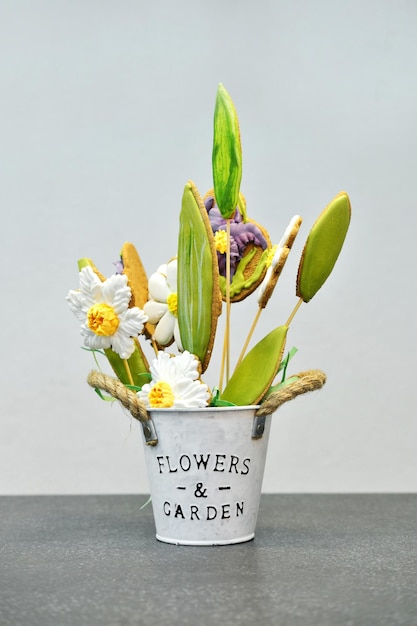 Een geschenkpot met peperkoek in de vorm van bloemen staat op een grijze tafel en op een grijze achtergrond Verticale foto