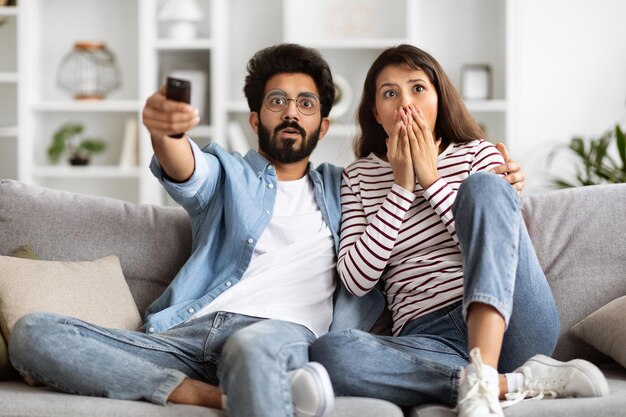 Een geschokt Indisch echtpaar kijkt thuis samen tv.