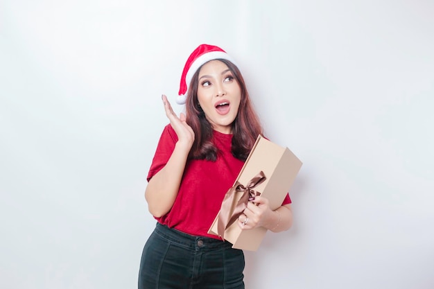 Een geschokte jonge vrouw draagt een hoed van de Kerstman39 en houdt kerstcadeautjes vast