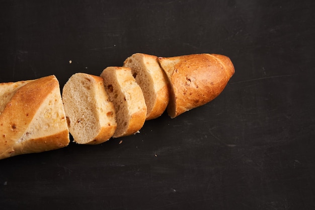 Een gesneden knapperige Franse baguettes liggen donkere zwarte tafel achtergrond sesamzaadjes Klassieke Franse nationale gebakjes