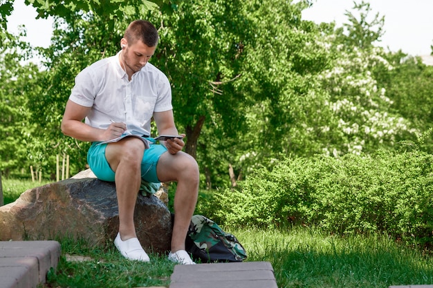 Een getalenteerde jonge kerel schrijft in de natuur, freelancen, frisse lucht