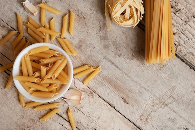 Een gevarieerd assortiment pasta op een houten ondergrond Foto van bovenaf