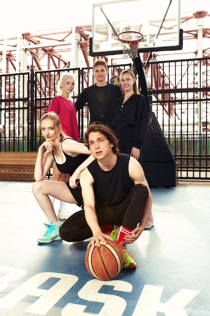 Een gezellig gezelschap van jongens en meisjes vermaken zich op het basketbalveld, ze gaan basketballen