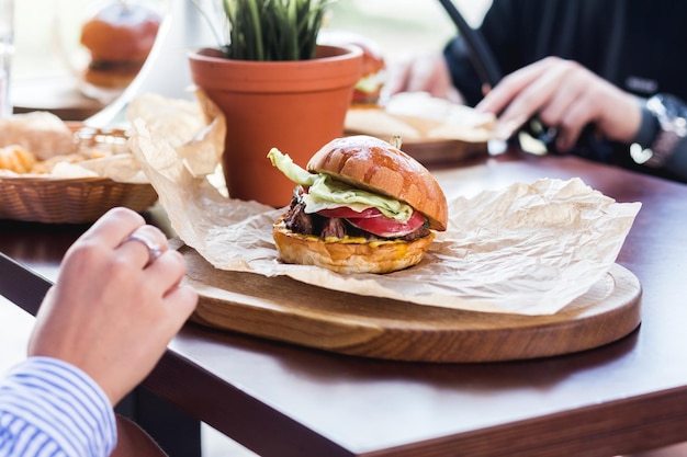 Een gezelschap vrienden ontmoette elkaar voor de lunch in een zomercafé, kletsend en hamburgers etend