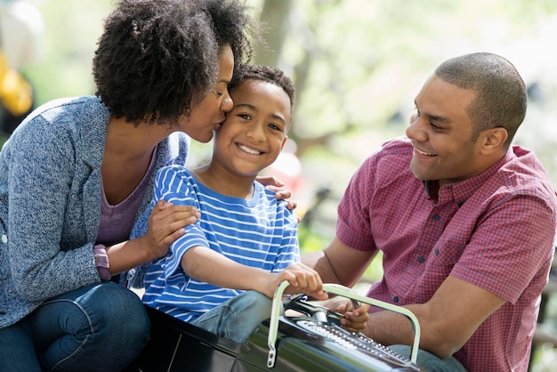 Een gezin in het park op een zonnige dag Een jongen die op een ouderwetse speelgoedauto rijdt