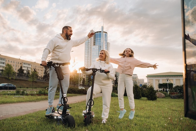 Een gezin in witte kleren staat in de stad op elektrische scooters.