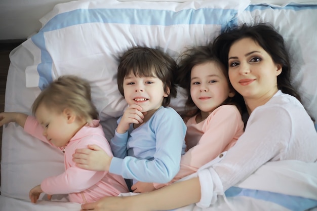 Een gezin met kinderen die zich tijdens de kerstvakantie op het bed onder de dekens vermaken.