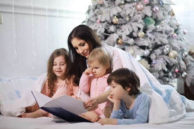 Een gezin met kinderen die zich tijdens de kerstvakantie op het bed onder de dekens vermaken.