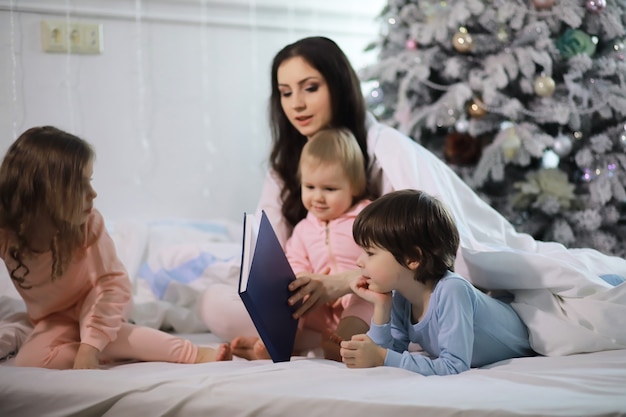 Een gezin met kinderen die zich tijdens de kerstvakantie op het bed onder de dekens vermaken.