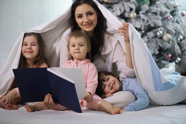 Een gezin met kinderen die zich tijdens de kerstvakantie op het bed onder de dekens vermaken