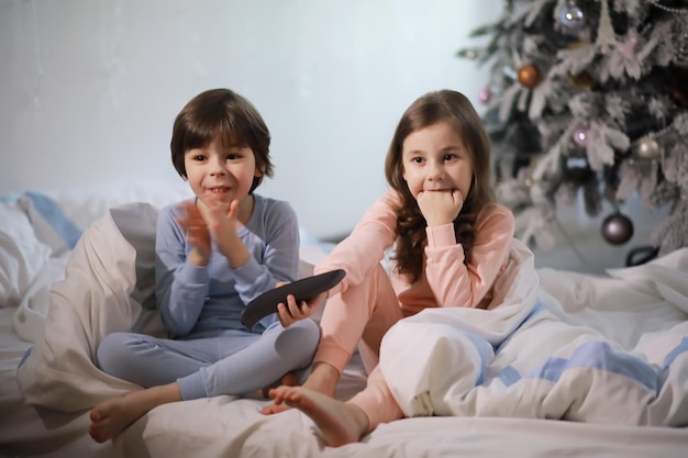 Een gezin met kinderen die zich tijdens de kerstvakantie op het bed onder de dekens vermaken