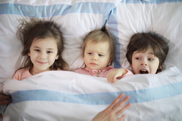 Een gezin met kinderen die zich tijdens de kerstvakantie op het bed onder de dekens vermaken