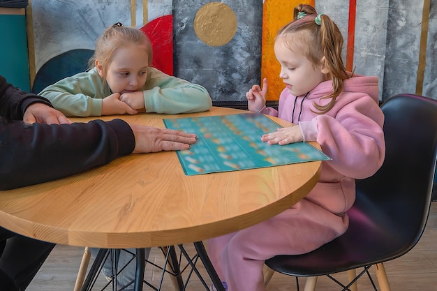 Foto een gezin met kinderen zit in een café en bestudeert het menu om eten te bestellen