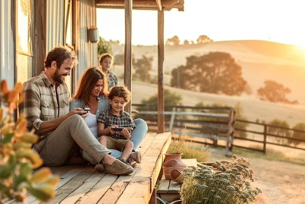 Een gezin past de smart home-controles aan op de veranda van een landelijk boerderijhuis met afstandsbediening en ene