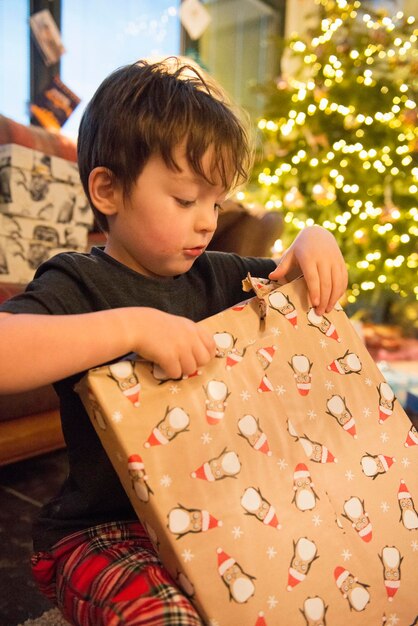 Een gezin thuis op eerste kerstdag Een jongen die een groot cadeau uitpakt