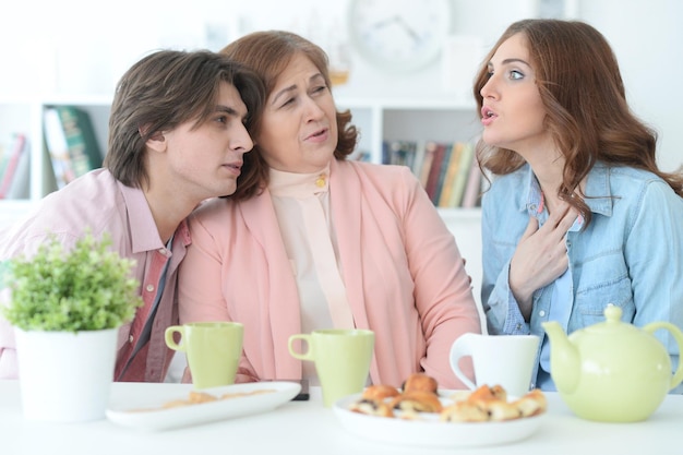 een gezin van drie personen die samen tijd doorbrengen aan de etentafel met koekjes en thee