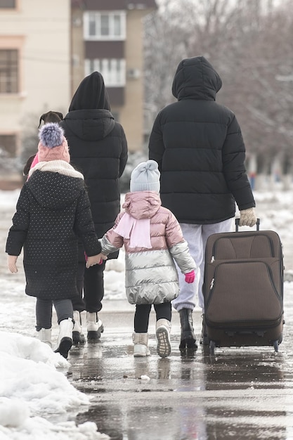 Een gezin van vier personen verlaat de stad voor een reis met een grote koffer in de winter