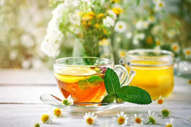 Een gezond kopje thee, een pot honing en bloemen. Selectieve aandacht.