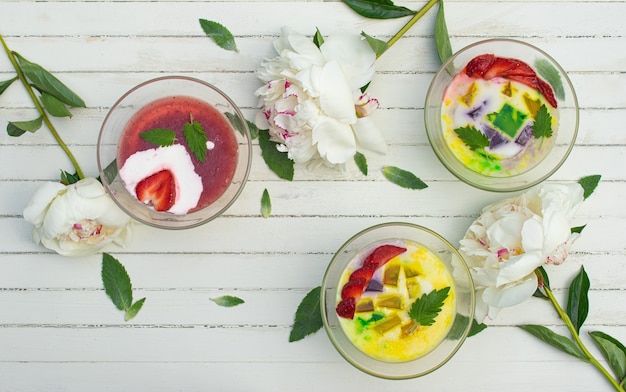 Een gezond ontbijt van melkgelei met vers fruit in glazen kommen op een rustieke tafel